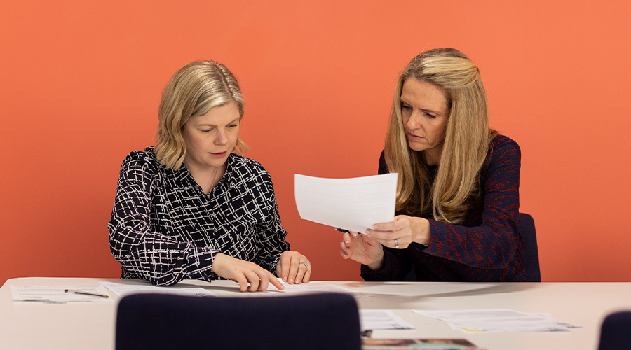 Lawyer and client sitting at desk, looking over documents