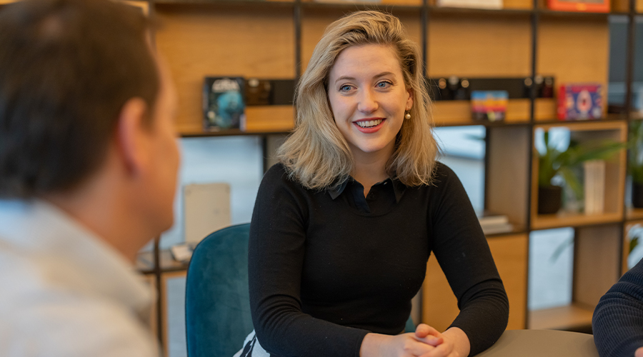 Female lawyer sitting at the table with clients, chatting and smiling