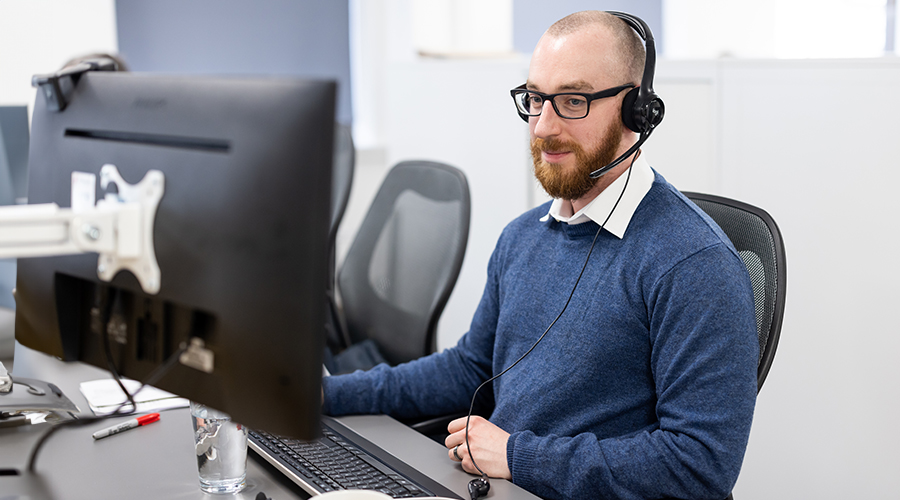 Man working on a computer with headset on