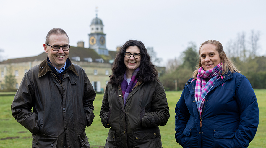 Group of three lawyers standing on a green field with church behind them in the distance