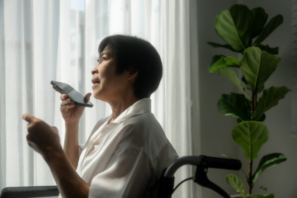 Asian mature woman holding insurance id card while speaking on the phone at home.