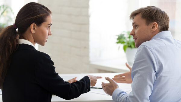 Two business people sitting at a desk, disusing important documents on the table (male and female, business people)