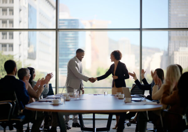 Two companies shaking hands as they form a merger