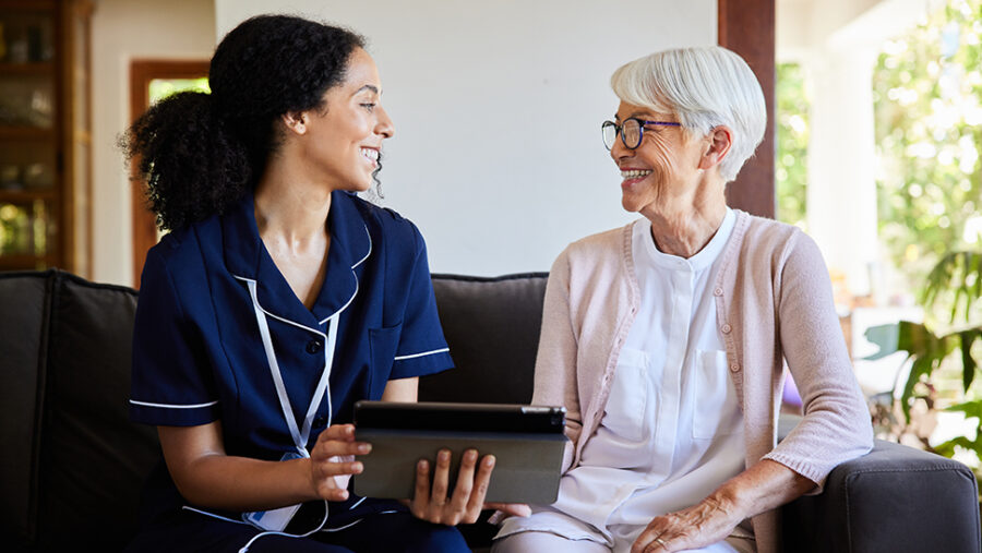 Care giver and elderly person sitting on the sofa chatting