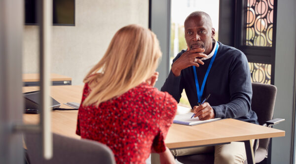 Teacher and parent sitting at at desk in a meeting room, disusing