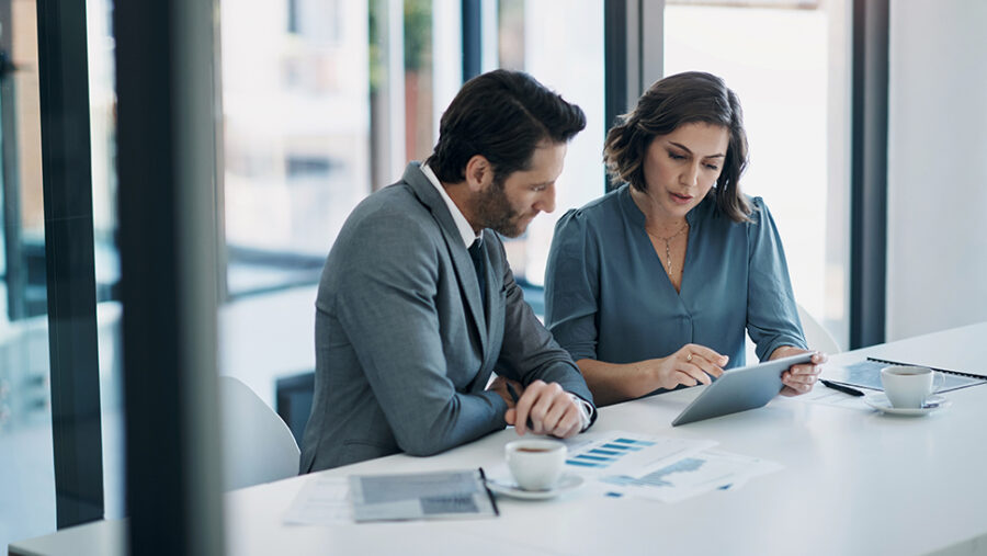 Business man and woman, sitting at a desk, in an office, looking over documents