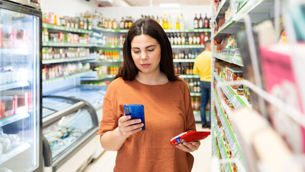 Female in supermarket reading the ingredients on the back of a product