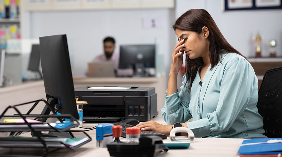 Female employer at desk, covering her eyes in disbelief