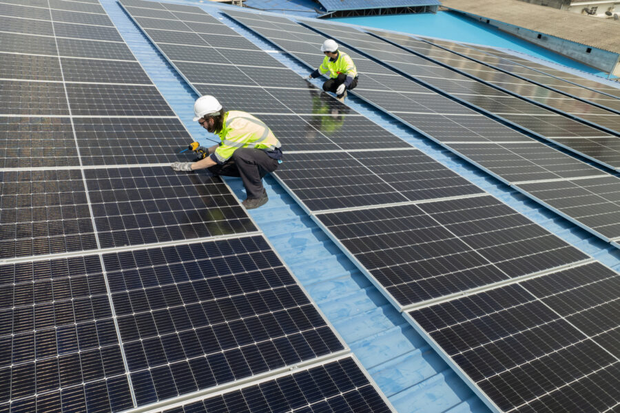 Contractors installing solar panels on a factory roof