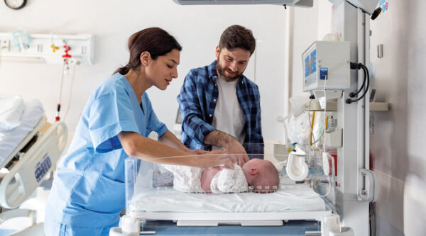 A father and nurse beside a newborn baby